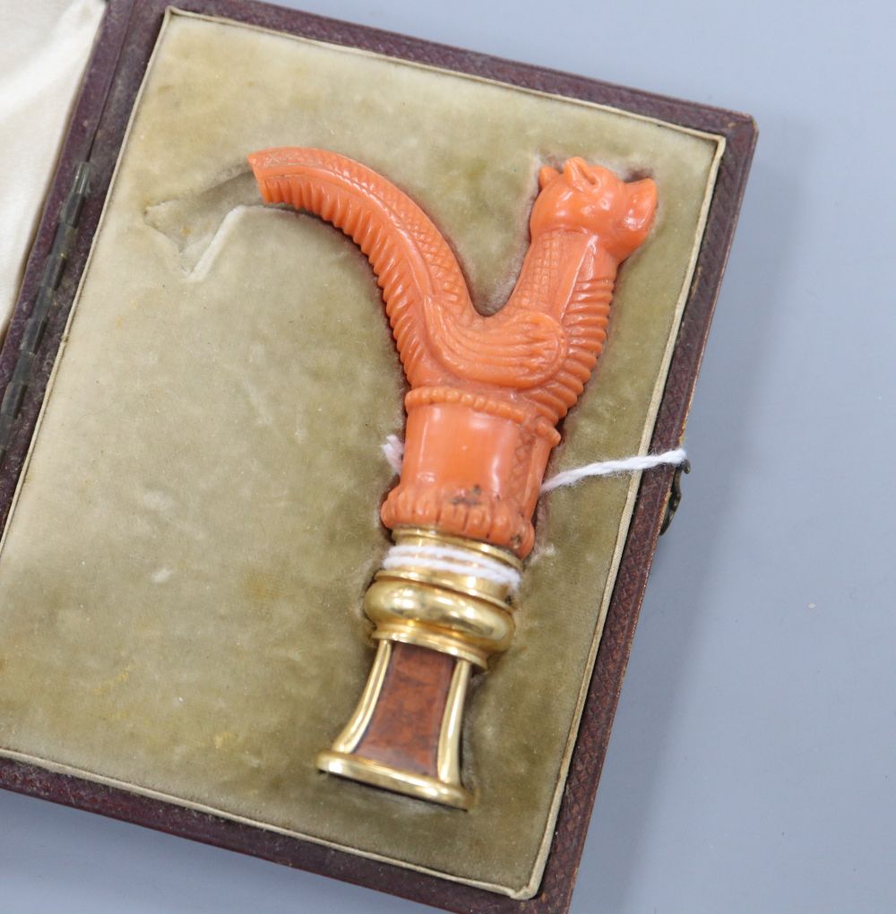 An early 20th century cased yellow metal mounted jasper seal with coral handle carved as a dragon (tail broken)